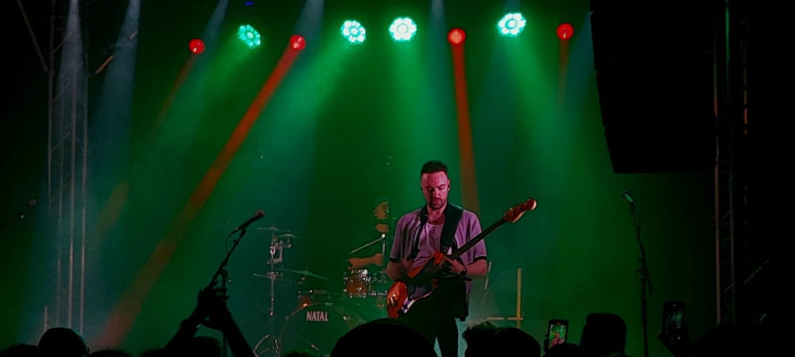 A band playing under green stage lights at Tucker's Grave